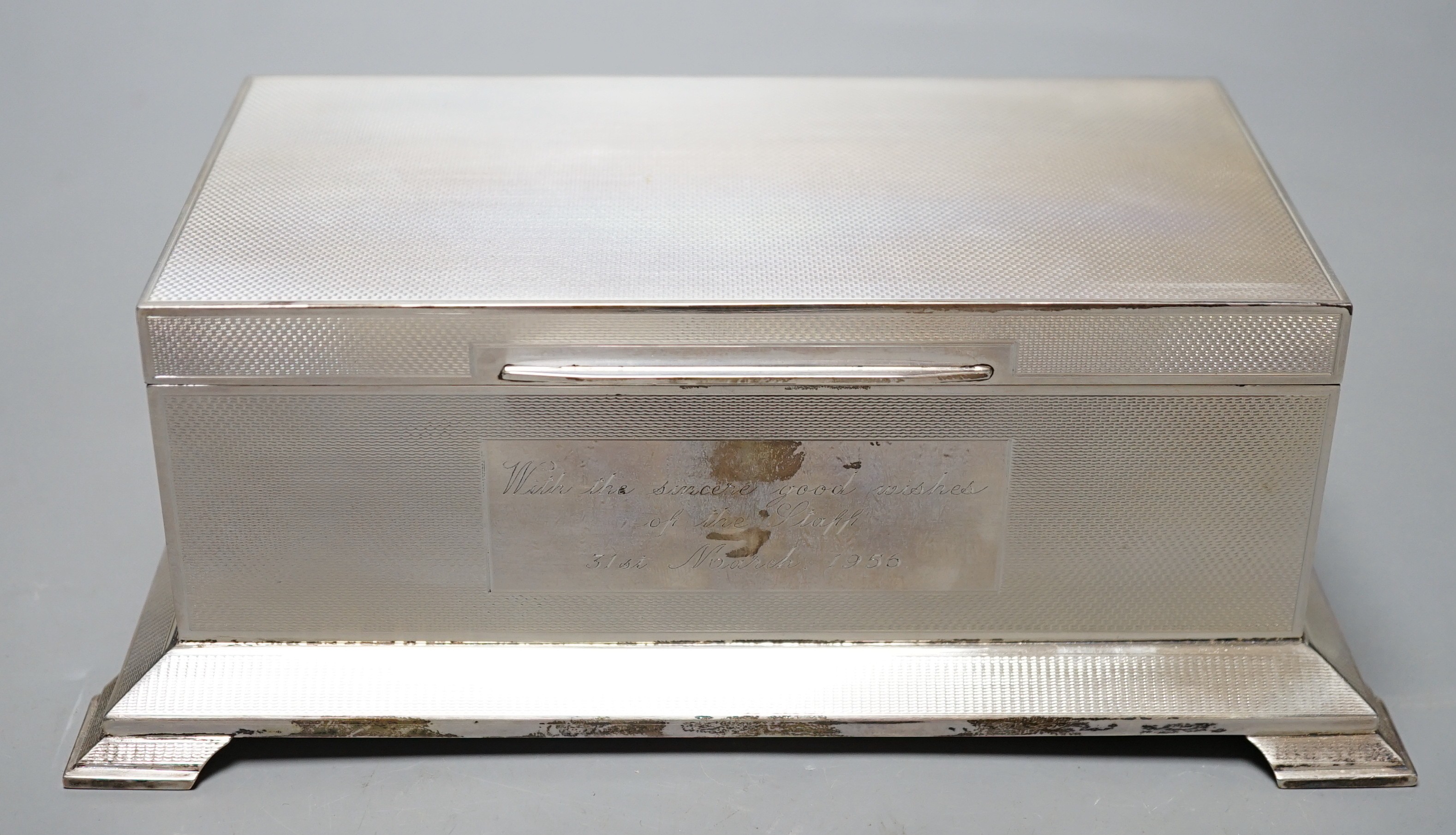 A George VI engine turned silver mounted rectangular cigarette box, Alexander Clark Co Ltd, Birmingham, 1948, with engraved inscription, on bracket feet, 20.4cm.